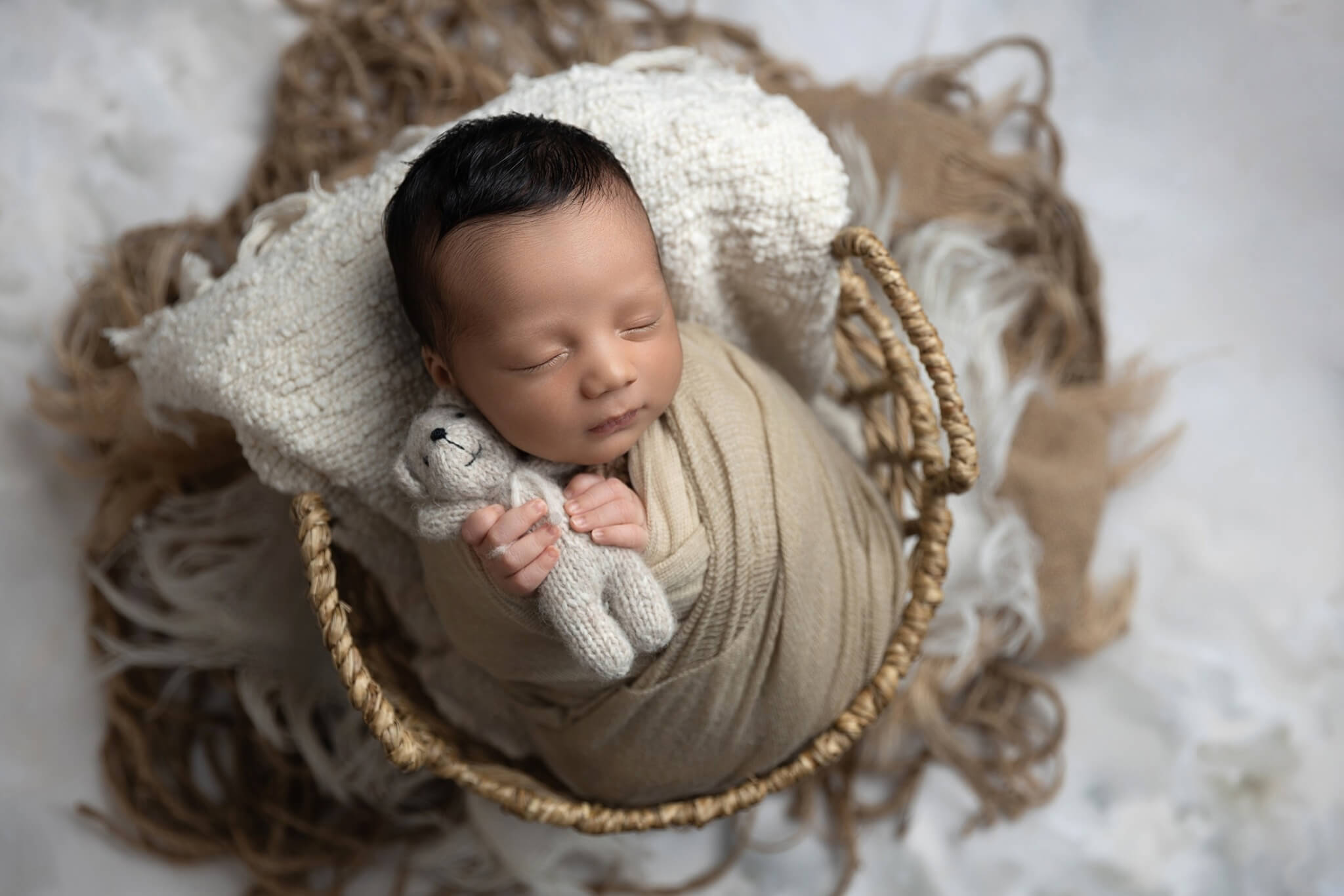 Photo of swaddled baby holding bear